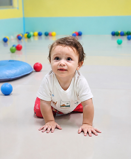 Bebê brincando com apoio de uma educadora na sala do berçário